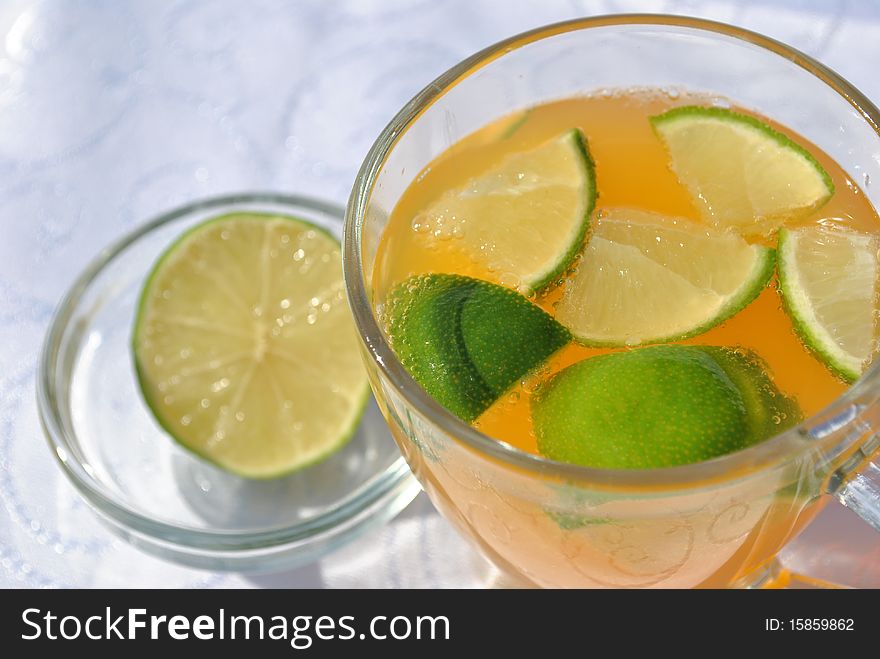 Image of some fresh orange juice with green lemons