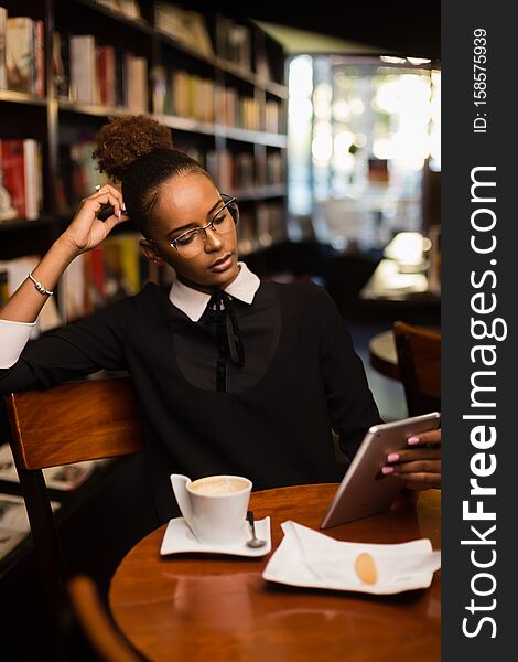 African american young yoman drinking coffee and using a tablet