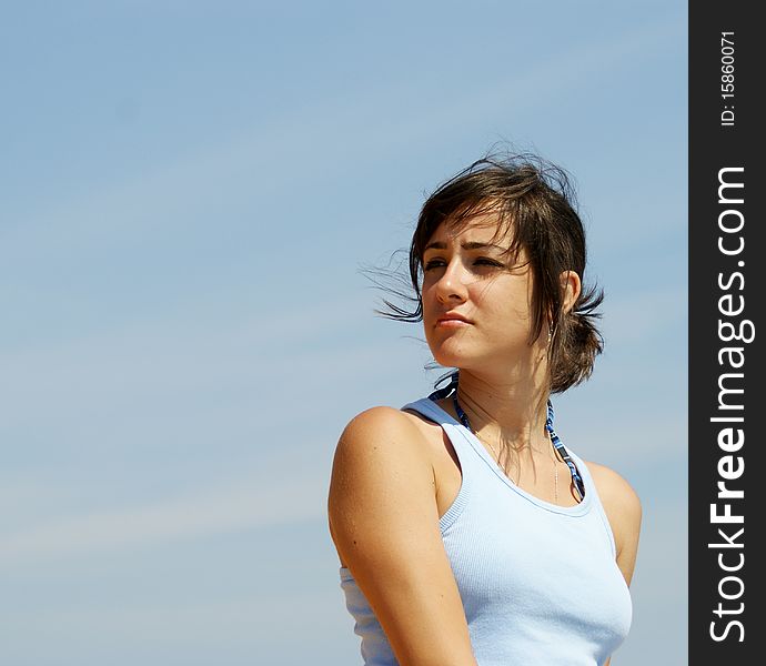 Portrait of a young beautiful woman near a seashore looking somewhere away in the distance. Portrait of a young beautiful woman near a seashore looking somewhere away in the distance