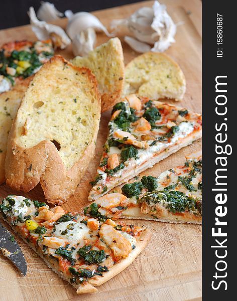 Slices of pizza with garlic bread on wooden board