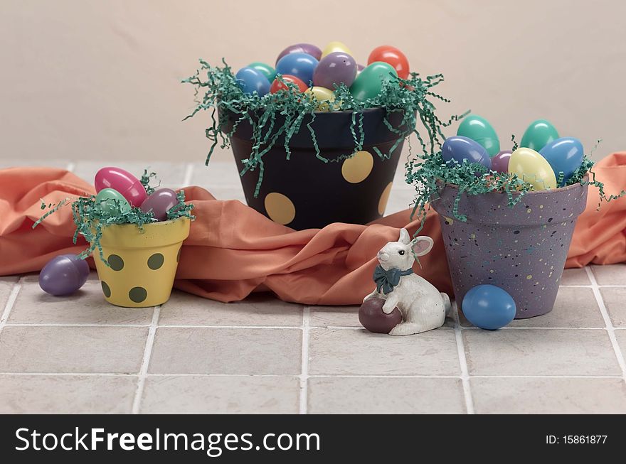 Three easter painted pots hold eggs and grass for the holiday