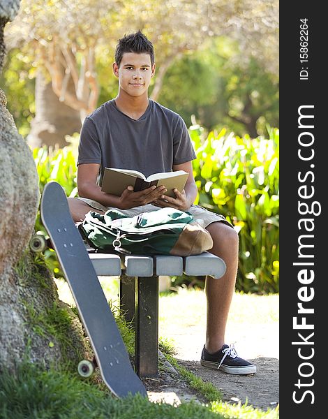 Student with skateboard and backpack at a park. Student with skateboard and backpack at a park