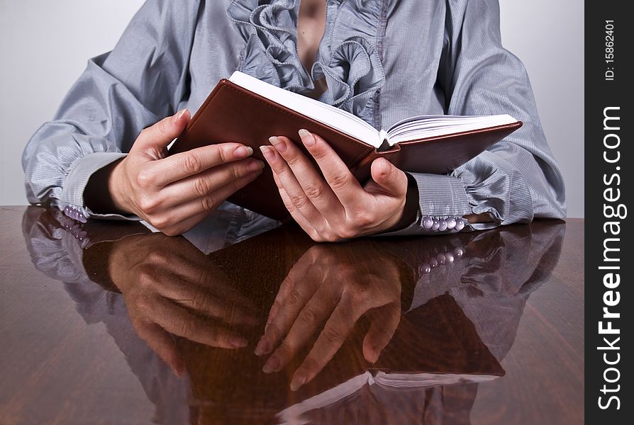 Businesswoman sitting at the desk and holding notepad in hands