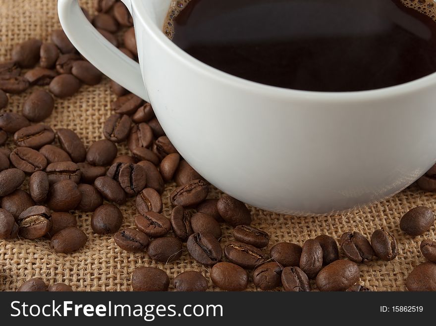 Coffee cup and coffee beans on a jute fabric