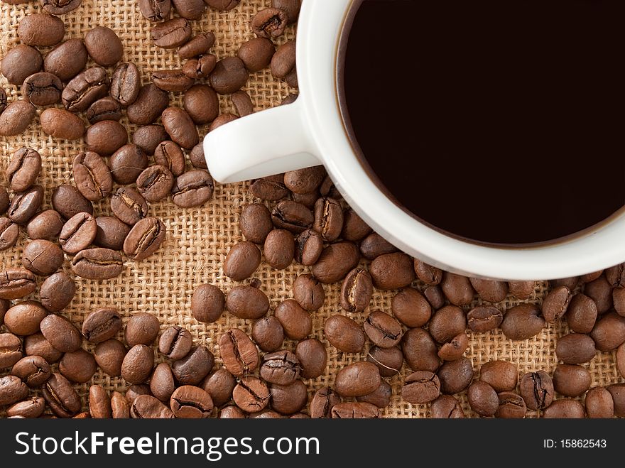 Coffee cup and coffee beans on a jute fabric