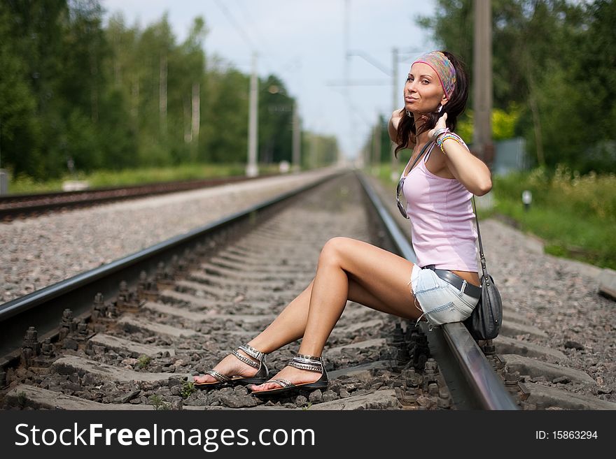 Young smiling lady is sitting on a railroad. Young smiling lady is sitting on a railroad