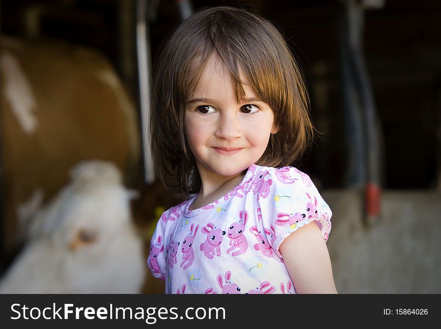 Portrait of a glittle girl with cow in background. Portrait of a glittle girl with cow in background