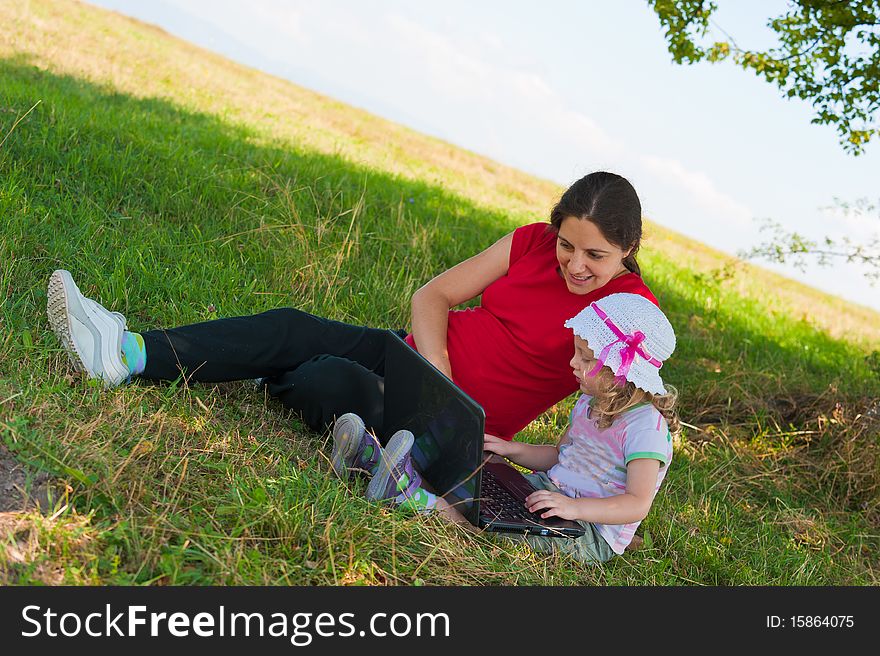 Mother and little girl outdoor with laptop