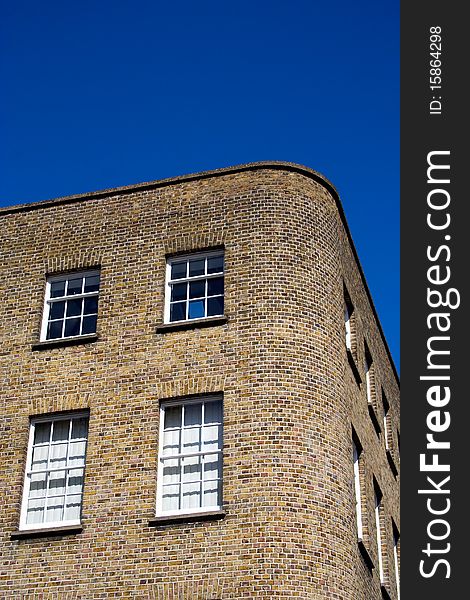 Corner of a brick building in an urban area under a blue sky. Corner of a brick building in an urban area under a blue sky.