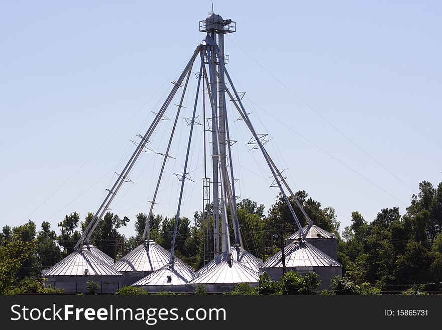 Dome roofed steel buildings grouped into a circle with a tower in the center and all connected to the center tower with pipes and cables, farming, grain bins, agriculture, environment. Dome roofed steel buildings grouped into a circle with a tower in the center and all connected to the center tower with pipes and cables, farming, grain bins, agriculture, environment