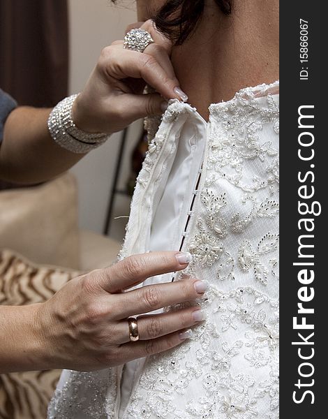 Girlfriend of the bride help to put on a wedding dress. Girlfriend of the bride help to put on a wedding dress