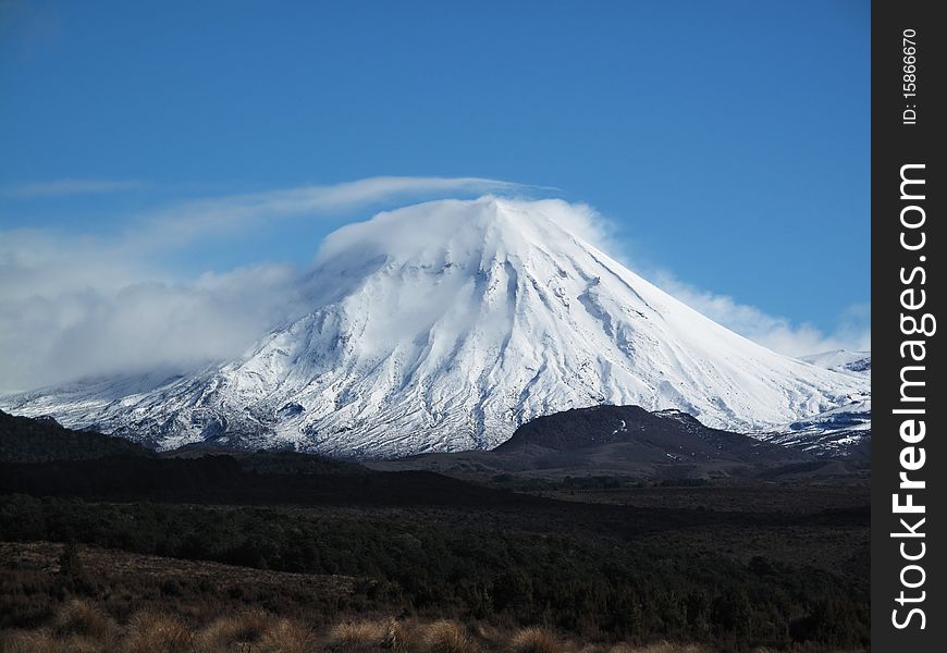 Mount Ngauruhoe covered in snow wearing a veil of cloud with tuntra in the foreground. Mount Ngauruhoe covered in snow wearing a veil of cloud with tuntra in the foreground