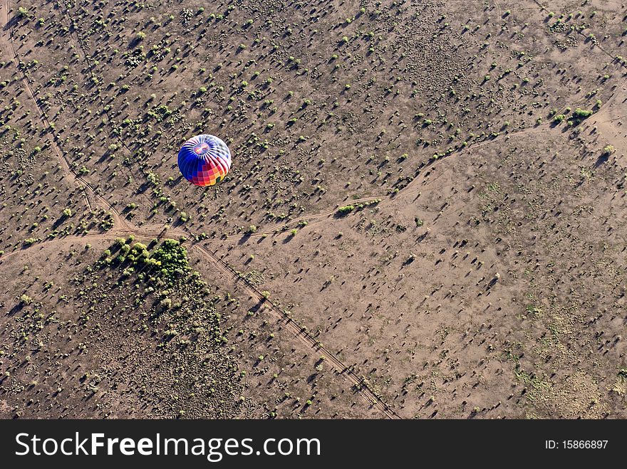 Aerial shot looking down on a hot air balloon as it crosses the desert. Aerial shot looking down on a hot air balloon as it crosses the desert.