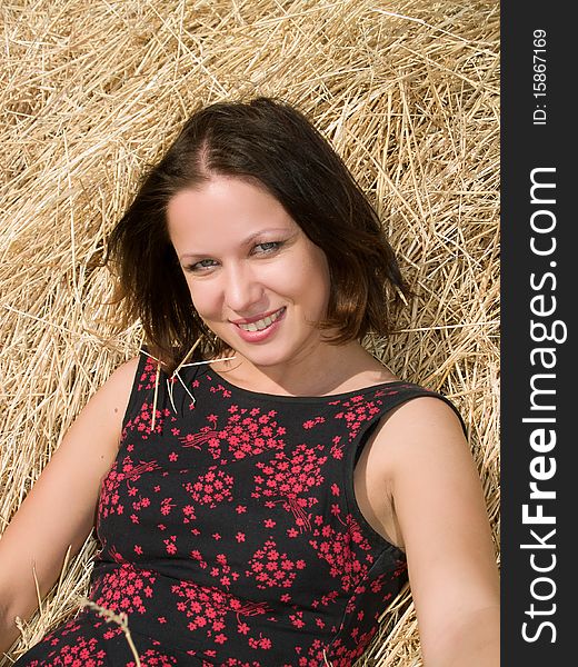 Beautiful young woman at a dry haystack