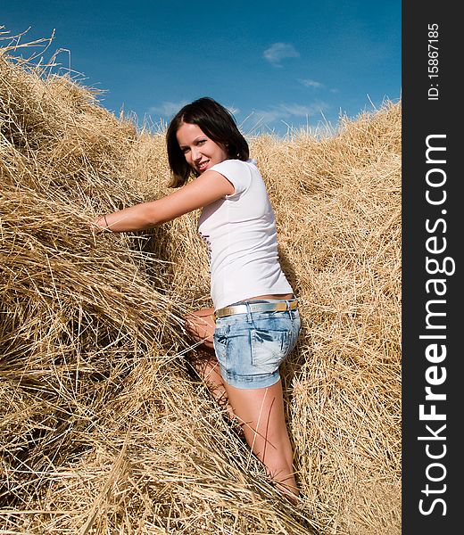 Beautiful young woman at a dry haystack