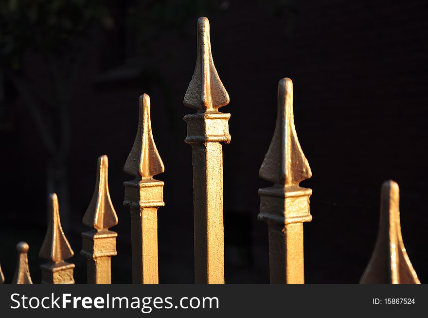 Shiny iron fence tops against dark background