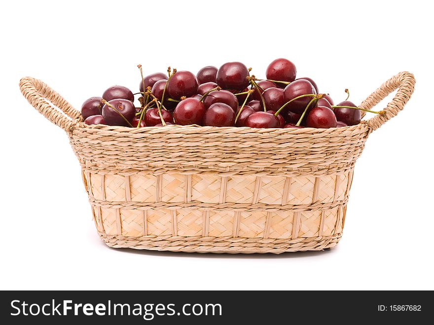 Red cherries in wooden basket isolated on white