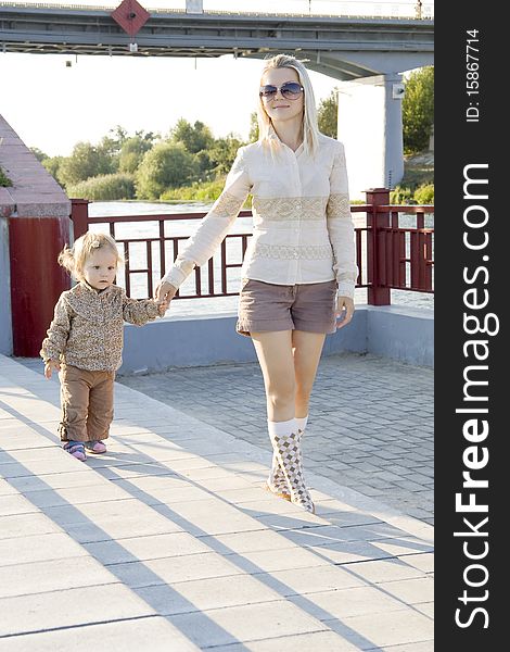 The woman with the child having joined hands walks on quay. The woman with the child having joined hands walks on quay