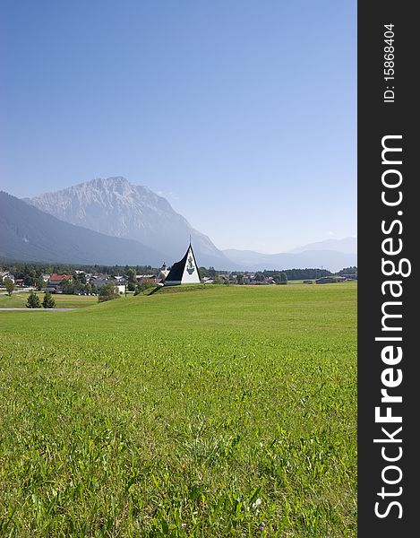 Alpine grassland with mountains and a small village in the background. Alpine grassland with mountains and a small village in the background.