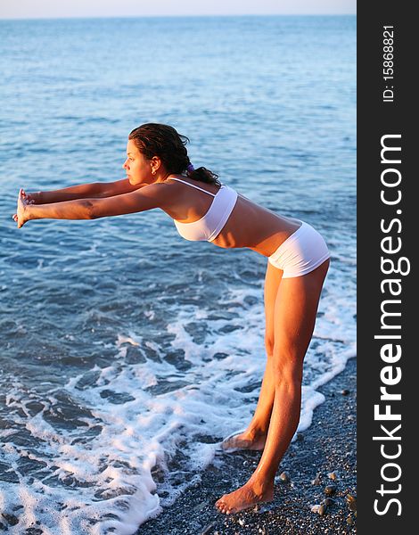 Beautiful brunette doing physical exercises on the beach. Beautiful brunette doing physical exercises on the beach.