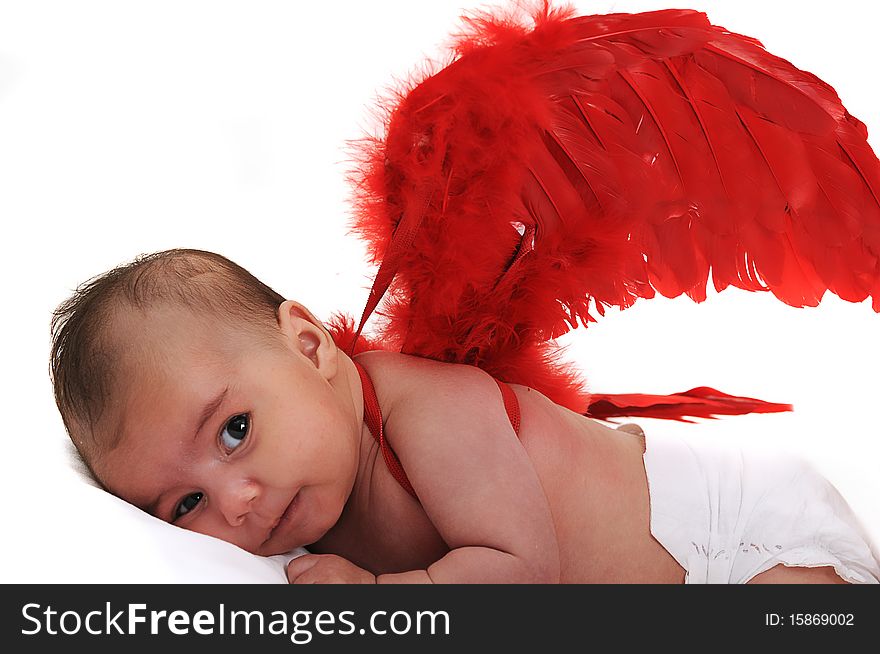 Baby in studio smiling and wearing red angle wings. Baby in studio smiling and wearing red angle wings