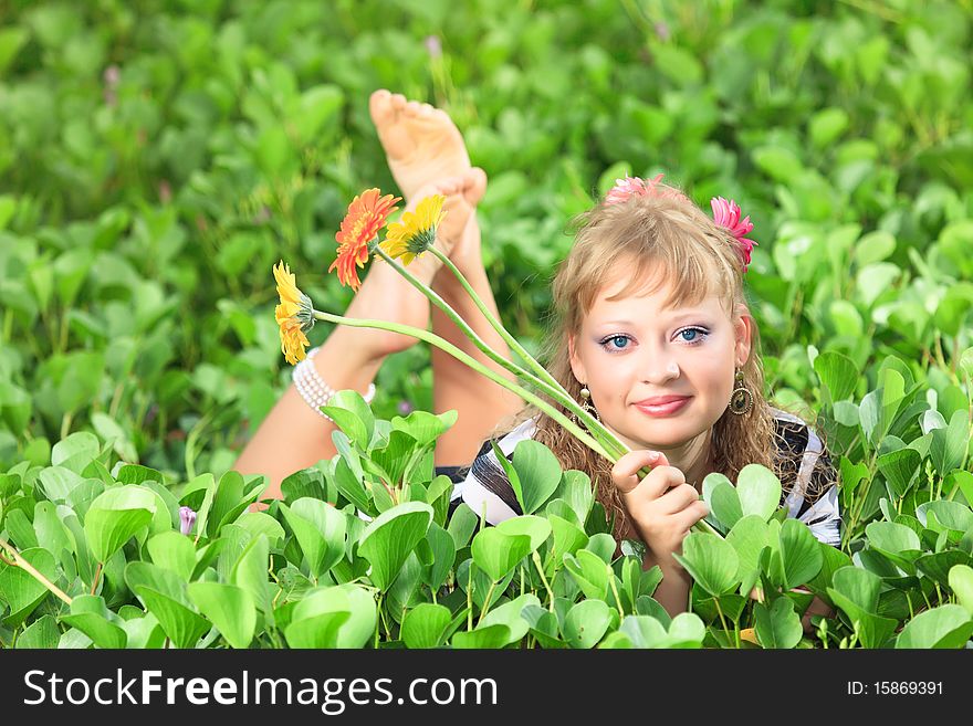 Beautiful woman in grass with gerbera flowers