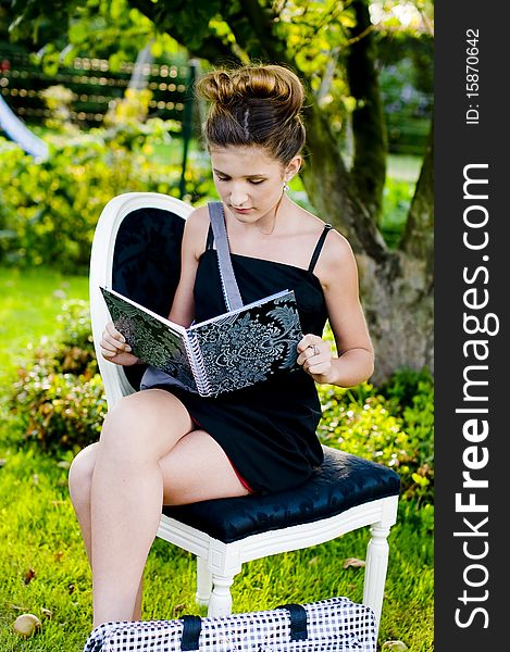 Back to school fashion showing girl reading class book in a black and white chair