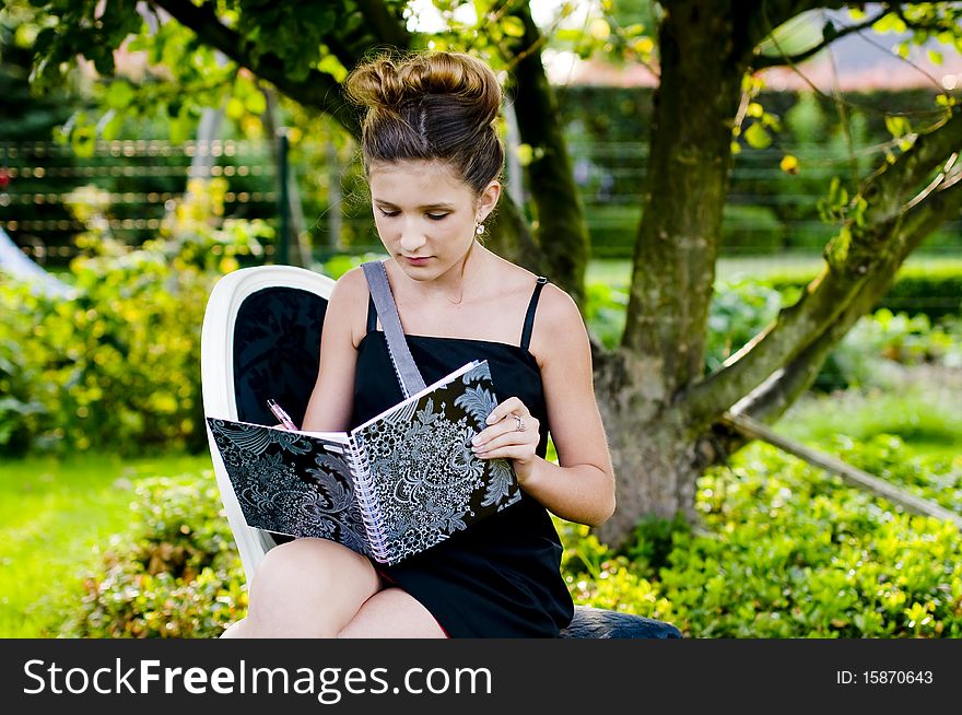 Back to school fashion showing girl reading class book in a black and white chair