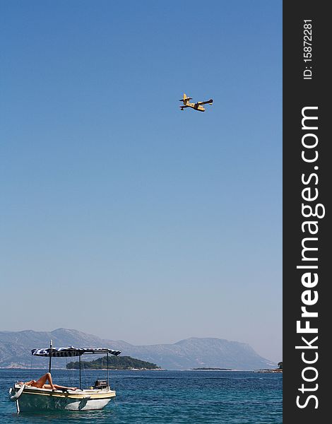 Landscape on the coast in Croatia with the boat in the foreground and the plane in the sky. Landscape on the coast in Croatia with the boat in the foreground and the plane in the sky