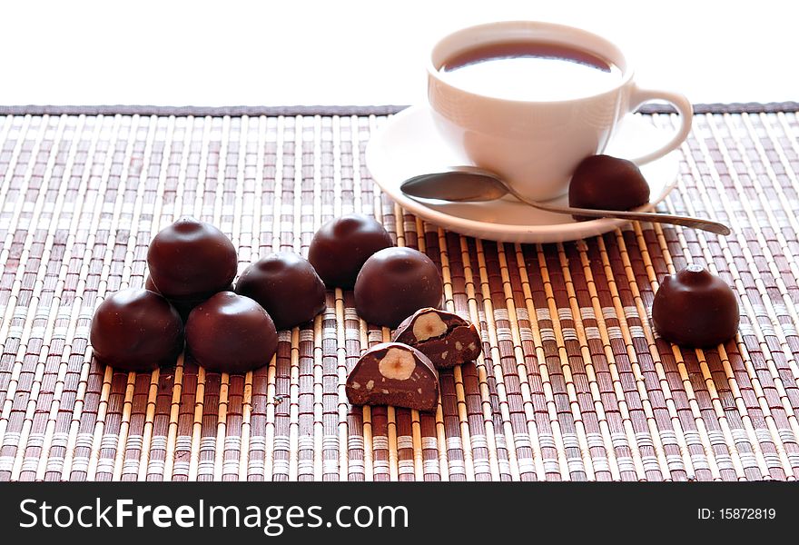 Chocolate candies with hazel-nuts alongside cup of coffee. Chocolate candies with hazel-nuts alongside cup of coffee