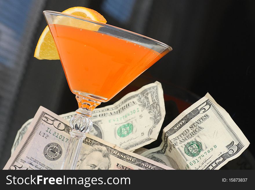 American dollar bills next to orange drink in martini glass. American dollar bills next to orange drink in martini glass