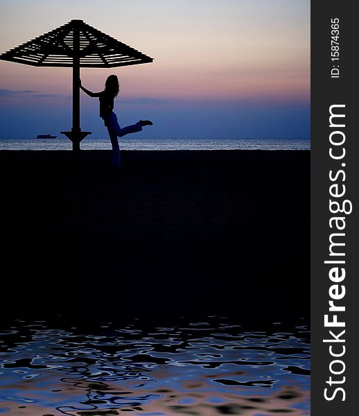 Beach umbrella and the girl silhouette on sunset. Beach umbrella and the girl silhouette on sunset