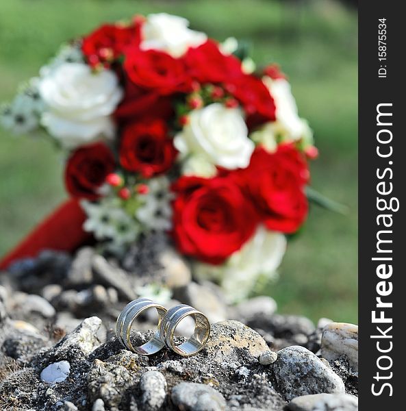 Wedding rings and bridal bouquet in the background