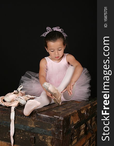 Cute little brunette girl trying on ballet pointe shoes. Cute little brunette girl trying on ballet pointe shoes