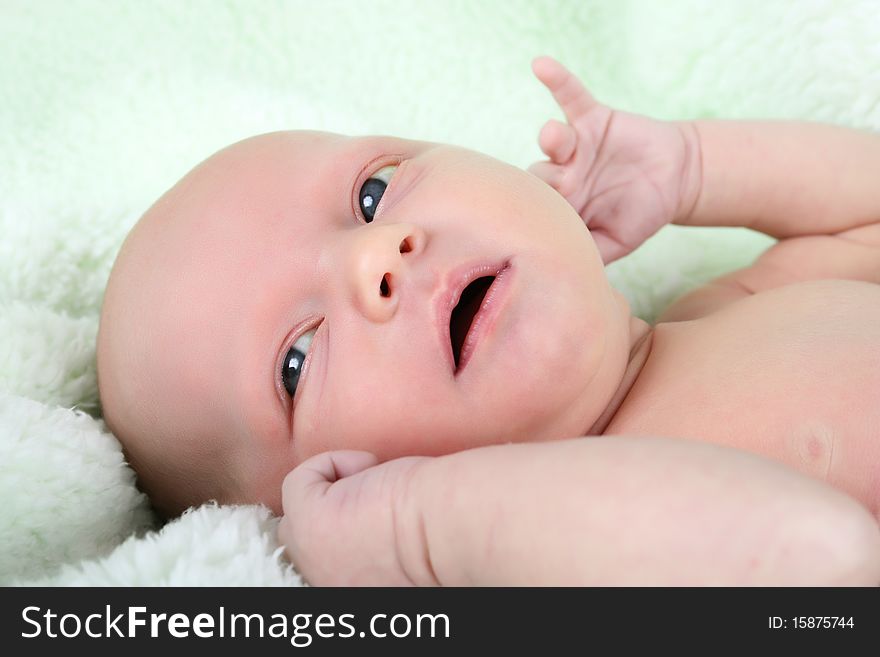 Beautiful newborn baby girl lying on a soft green blanket