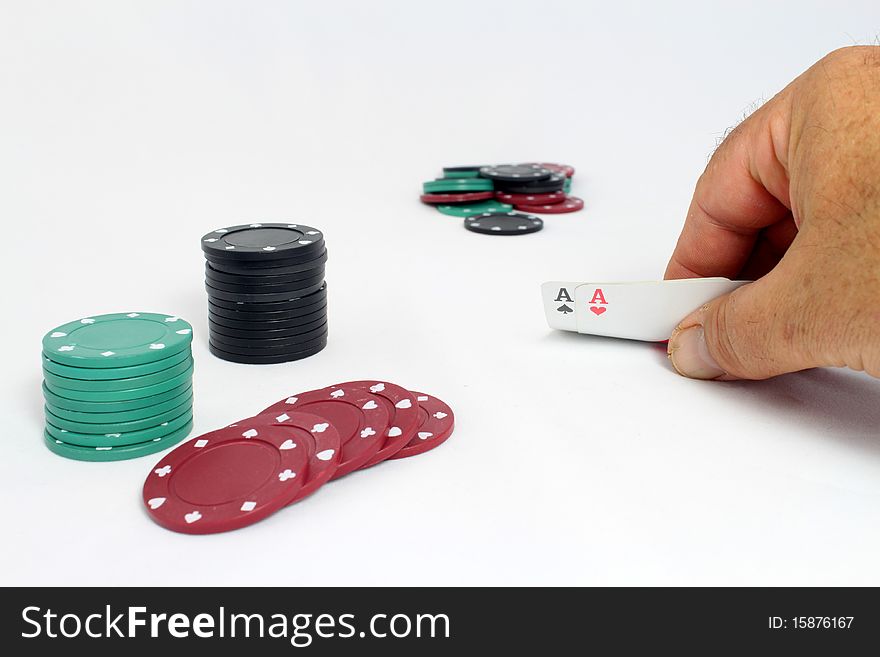 A game of poker, with a hand showing a pair of aces, player's chips close and pot out of focus in background. A game of poker, with a hand showing a pair of aces, player's chips close and pot out of focus in background