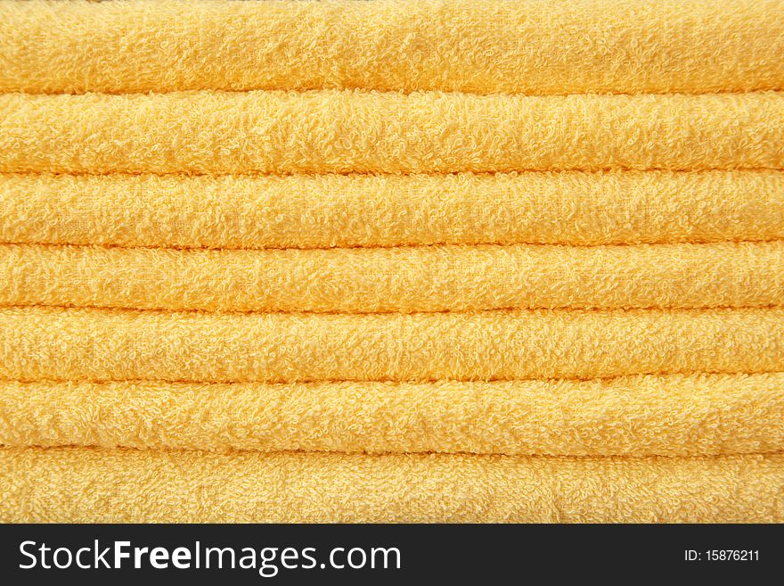 Yellow terry towels stacked in a pile.