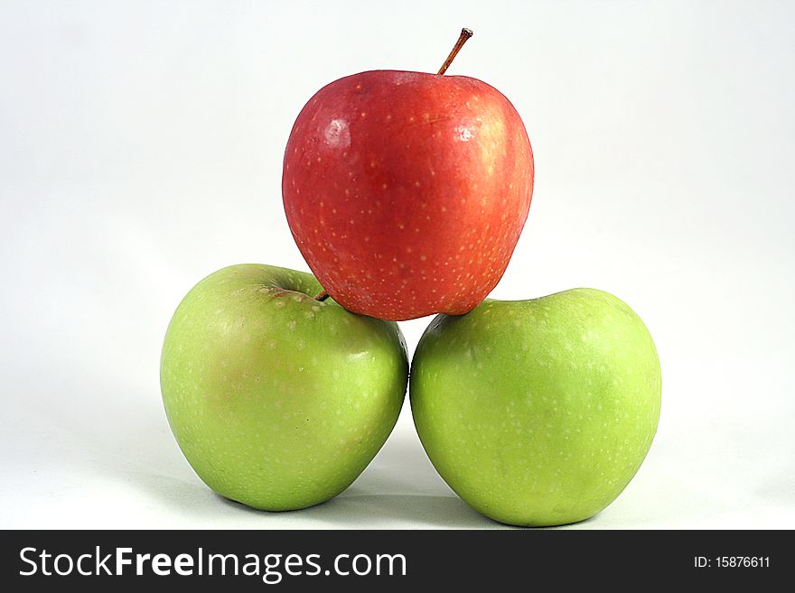 A red apple on top of two green ones. A red apple on top of two green ones.