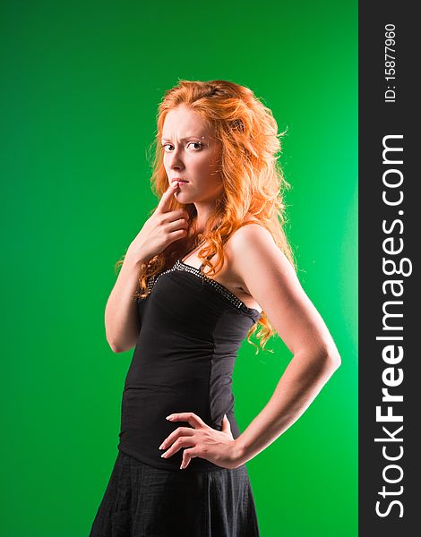 Beautiful red-haired woman with a worried look in black sarafan on a green background. Beautiful red-haired woman with a worried look in black sarafan on a green background