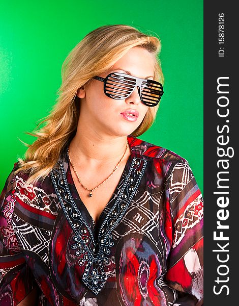 Beautiful young blonde in sunglasses on a green background. Beautiful young blonde in sunglasses on a green background
