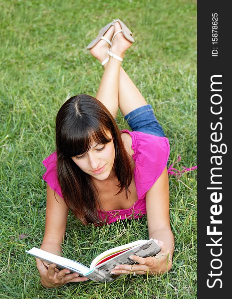 Young woman lying reading a book in grass outdoor. Young woman lying reading a book in grass outdoor