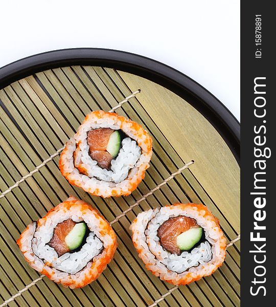 3 pieces of sliced sushi with vegetable served on black tray with bamboo base. 3 pieces of sliced sushi with vegetable served on black tray with bamboo base.