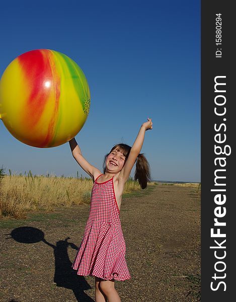 The little girl plays with the big ball. The little girl plays with the big ball