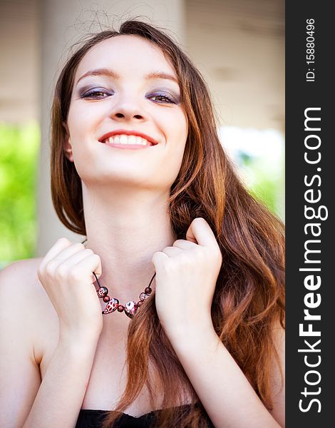 Portrait of a happy lovely young laughing girl wearing a necklace