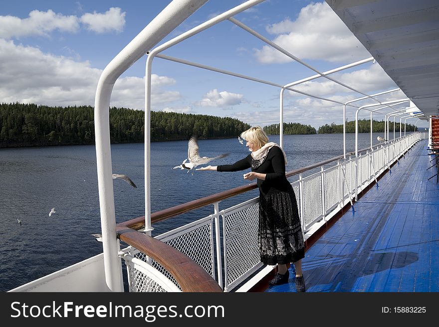 The woman onboard the steam-ship feeds seagulls. The woman onboard the steam-ship feeds seagulls