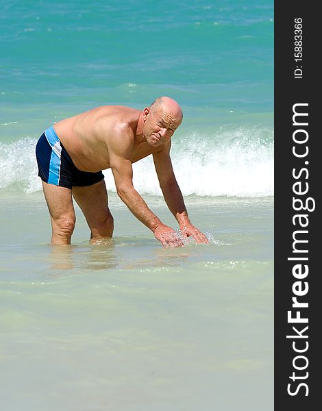 A senior man is standing in the water about to swim. Beach at Punta Cana, Dominican Republic. A senior man is standing in the water about to swim. Beach at Punta Cana, Dominican Republic.