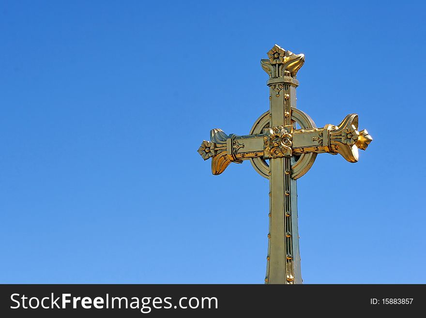 The golden cross on the Rosary Basilica in the holy catholic city of Lourdes in France with ancient castle in the background. The golden cross on the Rosary Basilica in the holy catholic city of Lourdes in France with ancient castle in the background.