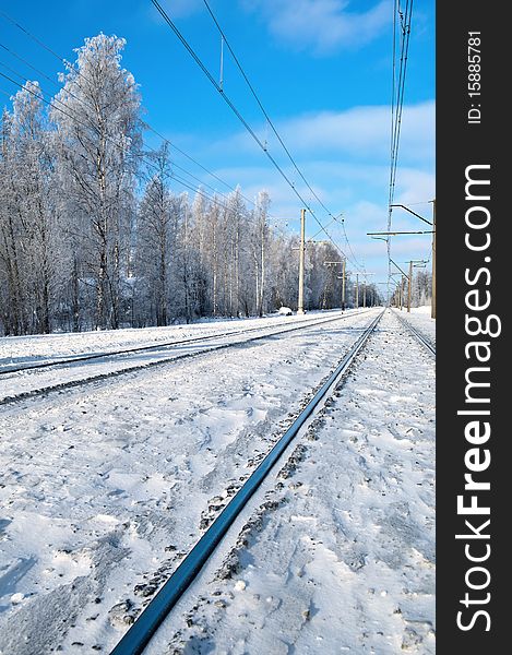 Railroad track against a background of snow-covered tree and blue sky. Railroad track against a background of snow-covered tree and blue sky.