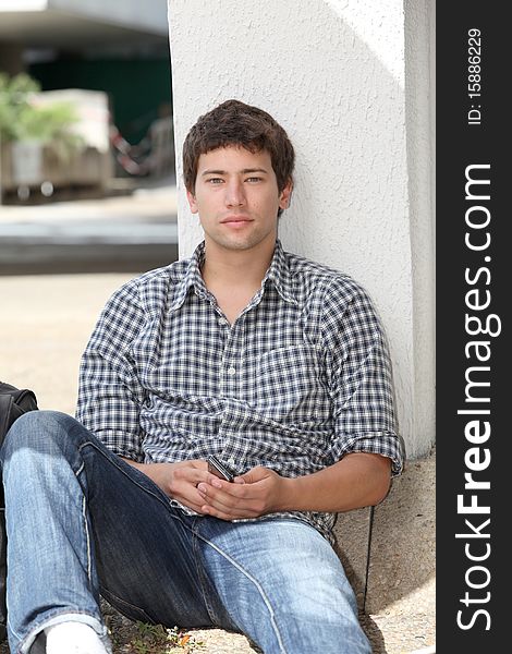 Young man sitting on the ground with mobile phone. Young man sitting on the ground with mobile phone