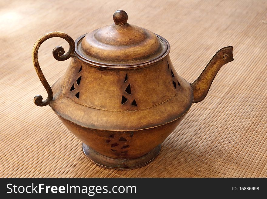 Old Brass teapot on a straw mat, close-up